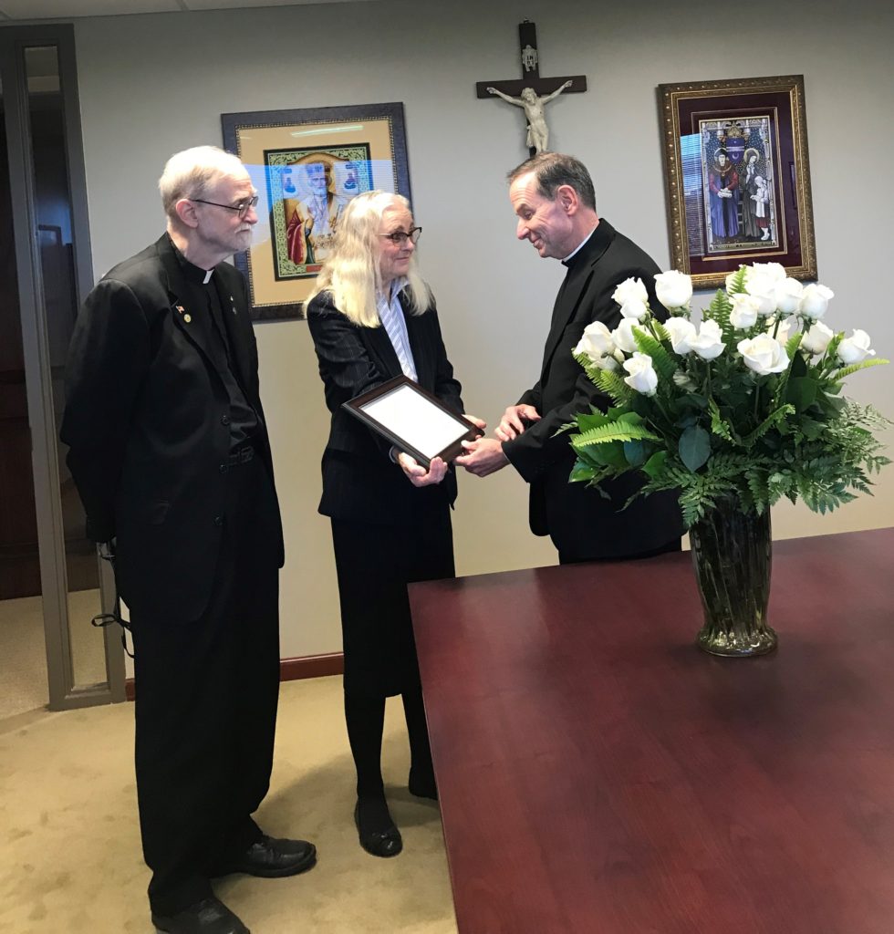 Bishop Burbidge is presented with the commendation of his defense of the God-given body from Ruth Institute President, Dr. Jennifer Roback Morse, and Ruth Institute Statistician, Father Paul Sullins. 