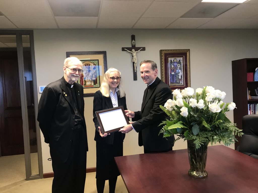 Bishop Burbidge receives two dozen white roses from Ruth Institute President, Dr. Jennifer Roback Morse, and Ruth Institute Statistician, Father Paul Sullins.
